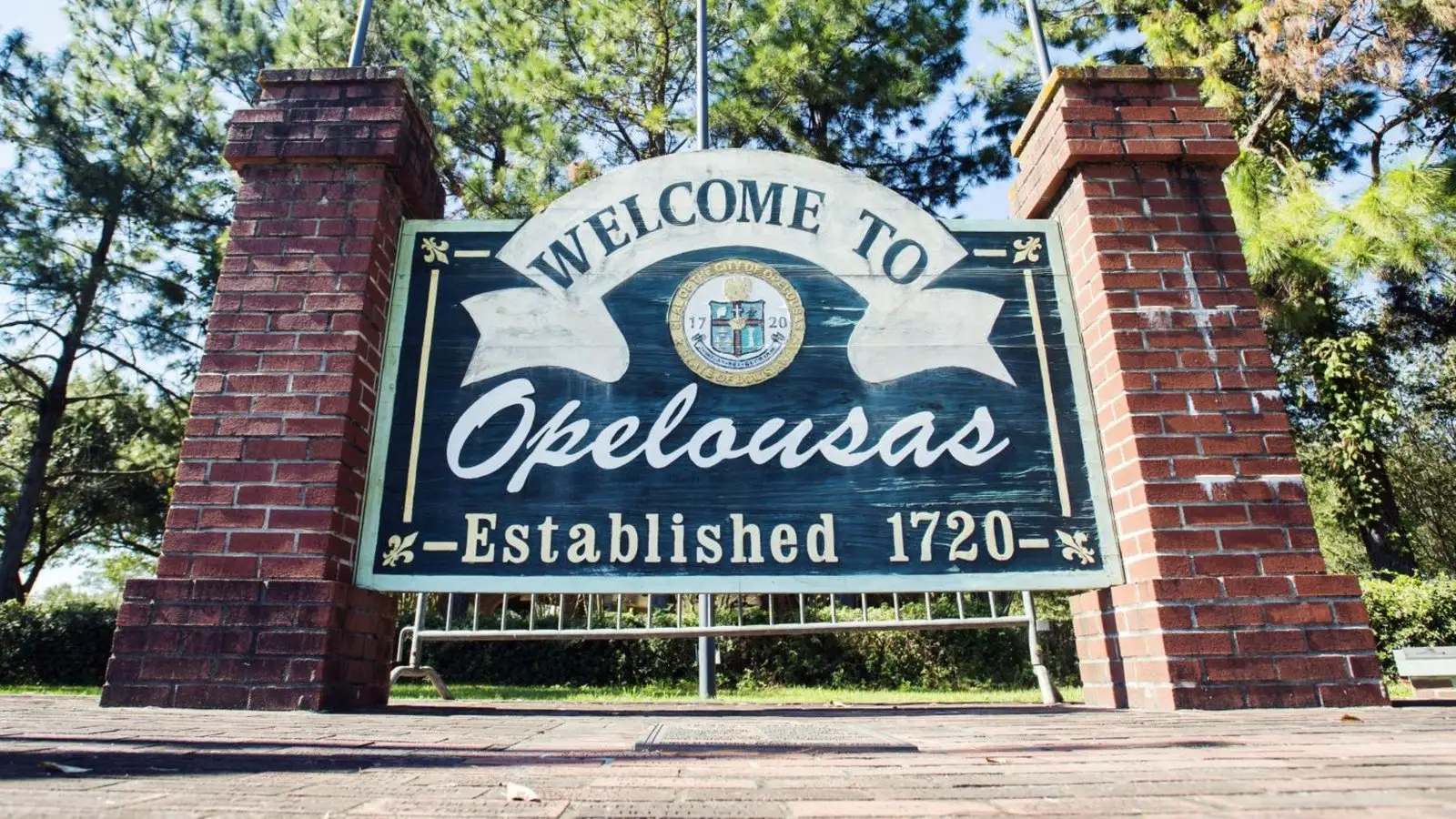 The Welcome to Opelousas sign, established 1720, a painted panel with the city seal set between two brick pillars